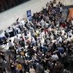 A crowd of people in a convention center are gathered in line.