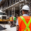 A construction worker watches as a cement truck comes through a construction site.