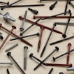 There is a lot of nails strewn across a wood surface.