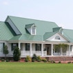 A house with a light green roof sits on a lawn.