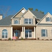 There is a pale brown house with a "for sale" sign.