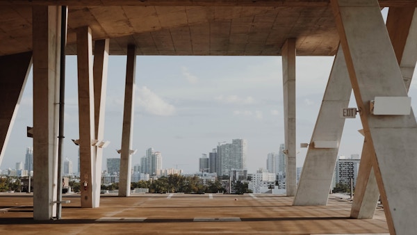 There is an unfinished structure with openings that reveal a view of a nearby city.