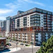 A city with an apartment complex on a street corner.