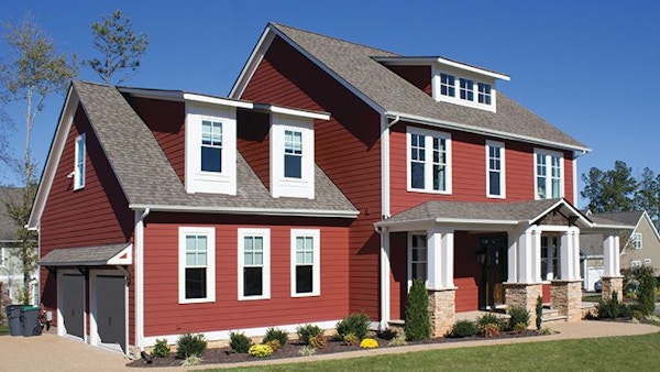 A red two story house sits in front of a lawn.
