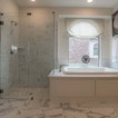 There is a bathroom with a glass shower and a bathtub.