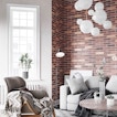 A brick living room with a window and a sofa alongside a reclining chair and a table.
