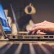 An unseen person types on a laptop.