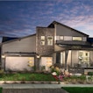 There is a gray house with the lights on while the sun sets.