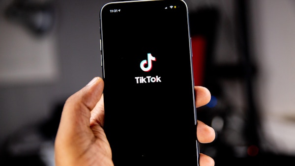 There is a phone with the Tiktok app being held by a hand.
