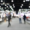 A fuzzy image of people walking on a convention center floor.