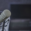 A close image of a microphone with a laptop in the background.