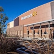 A Walmart storefront with a few plants and a tree in front of the street.