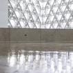 There is a ground view of a light brown background with a gray glass window on the light gray wall.