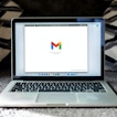 A laptop is open and shows Gmail loading.