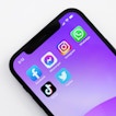 A phone with a purple background has six social media apps on the screen.