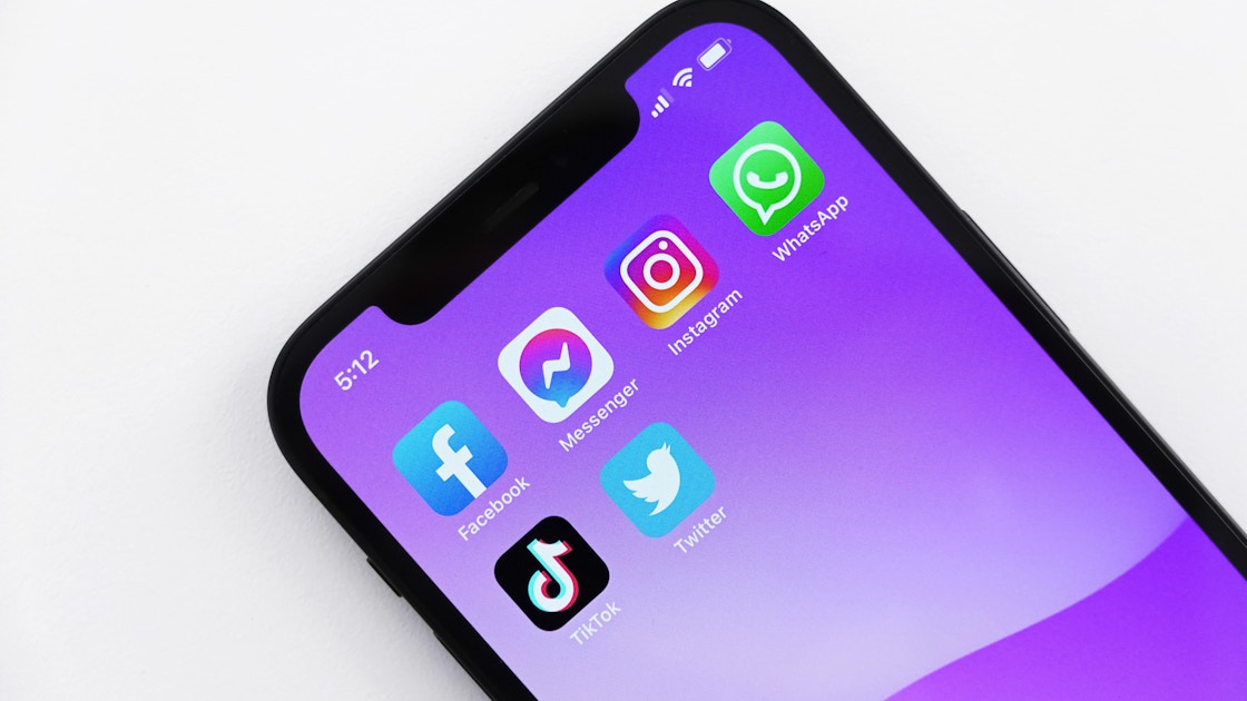 A phone with a purple background has six social media apps on the screen.