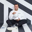 A man holding white paint sits in a black and white stripped room.