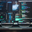 A pair of glasses sits in front of a computer.