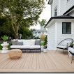 There is a deck with a sofa and two chairs. Behind it is a white house.