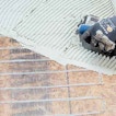 A hand brushes paste over a mesh net.